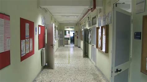 Foto di un'assemblea pubblica o di una scuola con un crocifisso appeso al muro, con persone di diverse età e provenienze