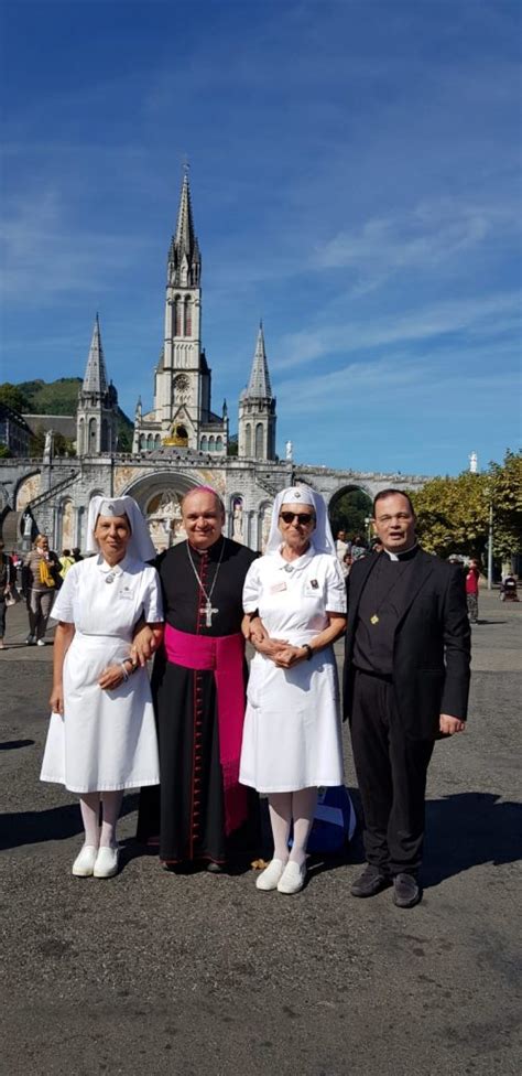 Foto di gruppo di volontari UNITALSI con pellegrini di fronte al Santuario di Lourdes