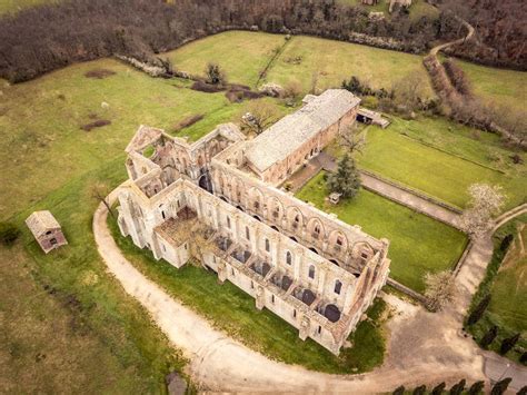 Foto aerea dell'Abbazia di San Galgano, evidenziando l'architettura senza tetto e il contesto paesaggistico toscano