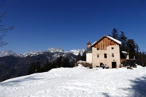 Foto panoramica invernale del Rifugio Eremo dei Romiti con la neve e le vette dell'Antelao sullo sfondo