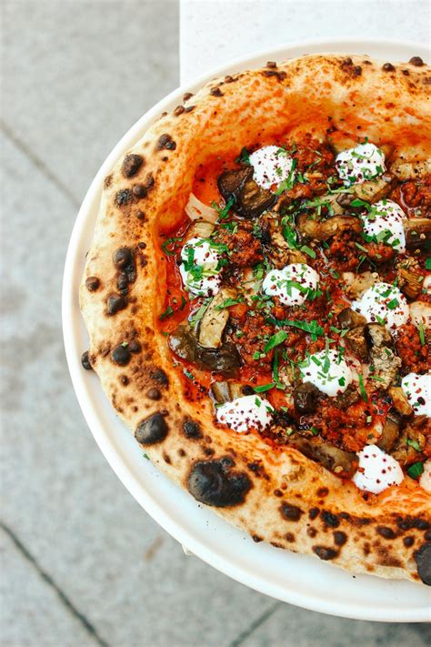 Dettaglio di una pizza gourmet con ingredienti freschi di stagione e cornicione a regola d'arte.