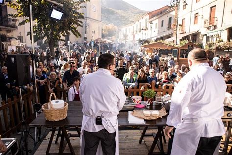 Fotografia di una tavolata all'aperto durante una sagra veneziana con piatti tipici e partecipazione popolare