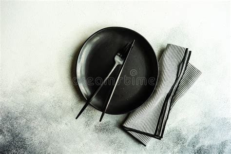 Dettaglio della mise en place minimalista con tovagliolo, posate e bicchiere