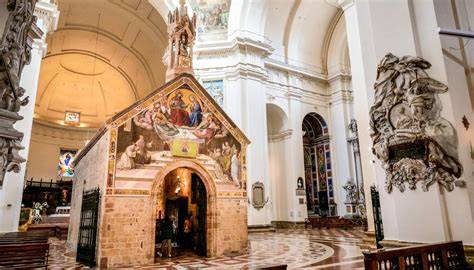 Foto esterna della moderna chiesa della Porziuncola a Platja de Palma, che ne evidenzi l'audace architettura in cemento.