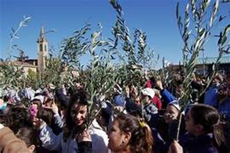 Foto panoramica della processione della Domenica delle Palme sul Monte degli Ulivi a Gerusalemme, con fedeli che portano palme e rami di ulivo.