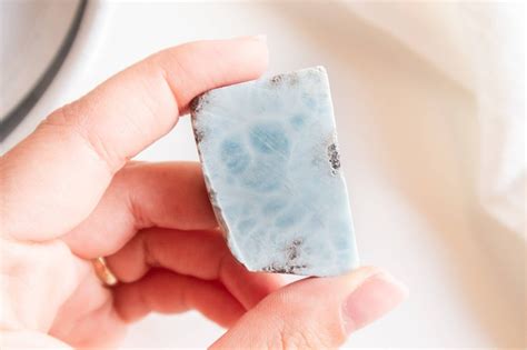 Foto ravvicinata di pietre Larimar grezze e levigate, che mostrano le sfumature di blu e bianco