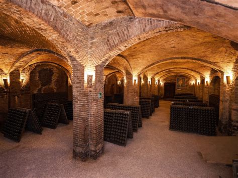 Foto suggestiva delle gallerie sotterranee con volte in mattoni e bottiglie in affinamento