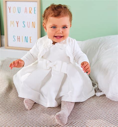 Tematica: bambina felice in un abito da battesimo bianco, stile delicato