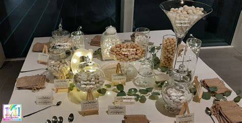 Tavolo della confettata per battesimo con decorazioni a tema pastello e contenitori in vetro