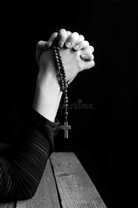 Mani che stringono un rosario con una luce soffusa