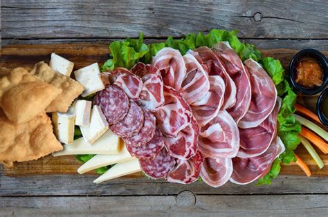 Foto di un tagliere di salumi e formaggi tipici modenesi con crostini e vino