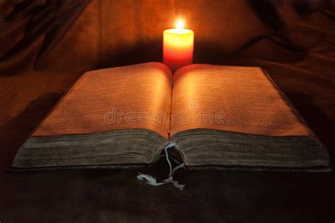fotografia di una Bibbia aperta accanto a una candela accesa in un ambiente accogliente