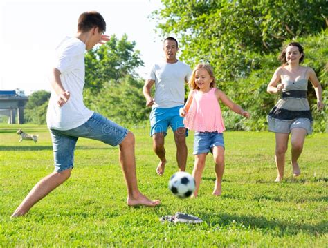 Foto di bambine che giocano a calcio, con genitori che assistono sorridendo