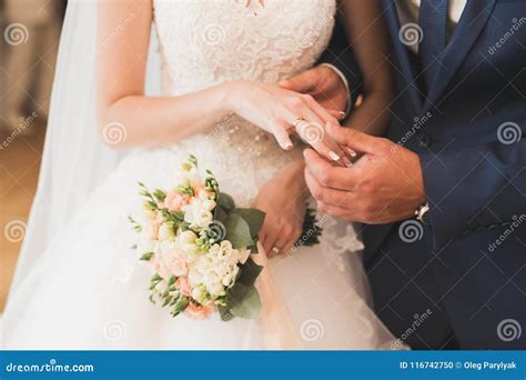 primo piano di mani che si scambiano fedi nuziali durante una cerimonia religiosa