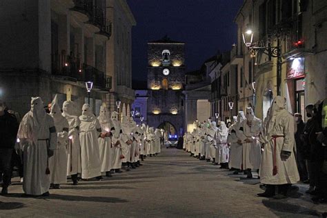 Immagine di confratelli incappucciati e a piedi nudi che sfilano per le vie di Taranto durante il pellegrinaggio nei Sepolcri.
