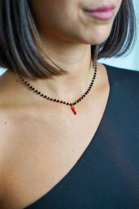 Collana stile rosario con perline nere e crocifisso argentato su sfondo neutro