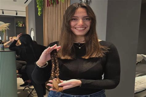 Giovane ragazza mentre dona i suoi capelli, con un sorriso di soddisfazione