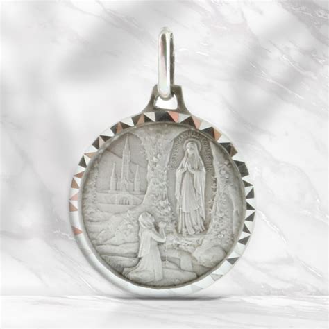 medaglia di Lourdes su sfondo sfocato di mani in preghiera