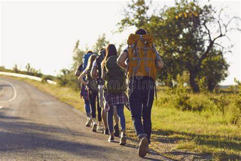 Foto di gruppo di giovani pellegrini in partenza, con zaini e bastoni da cammino