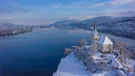 Foto panoramica di Maria Wörth al tramonto con le chiese illuminate e il lago Wörthersee