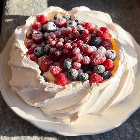 Una Pavlova bianca decorata con frutta fresca e panna