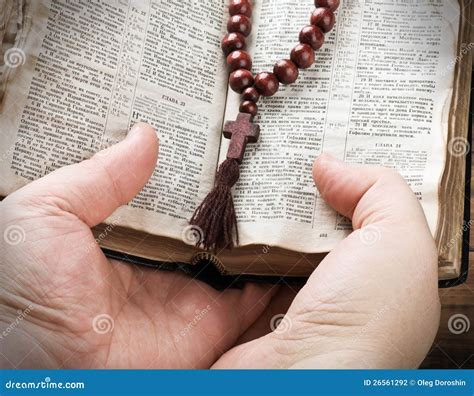 Mani che pregano il Rosario, con sfondo sfocato di un crocifisso