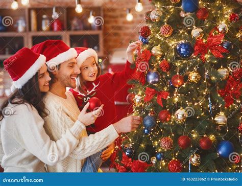 Foto di famiglia che addobba l'albero di Natale insieme