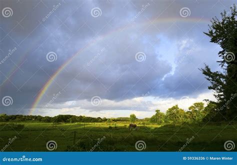 Un arcobaleno che appare sopra un paesaggio dopo un temporale.