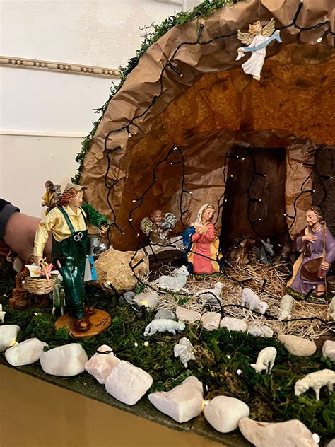 Mani che posizionano una statuina in un presepe, simboleggiando cura e tradizione