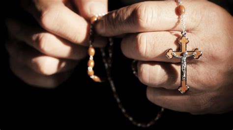 Un rosario tenuto tra le mani, simbolo della preghiera mariana