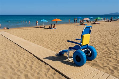 Foto di spiaggia accessibile con passerelle e persone in sedia a rotelle che godono il mare