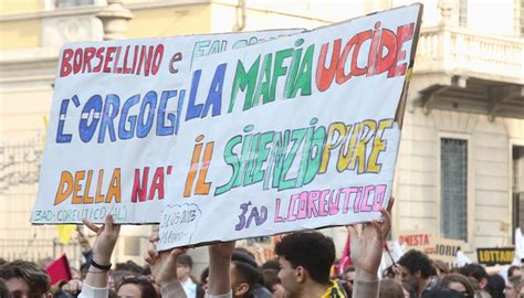 Manifestazione pubblica con striscioni e folla in ricordo delle vittime