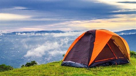 Foto di bambini che montano una tenda in un campeggio, con educatori che li supervisionano.
