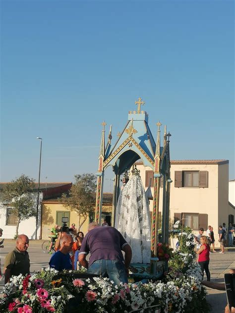 Colorata processione religiosa in un borgo sardo, con il simulacro della Madonna Assunta portato a spalla e fedeli in abiti tradizionali