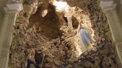 Interno della Grotta di Massabielle con fedeli in preghiera