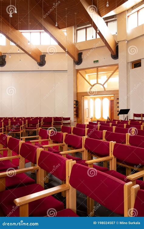 Fedeli seduti in panchina in una chiesa moderna, alcuni con espressione di riflessione