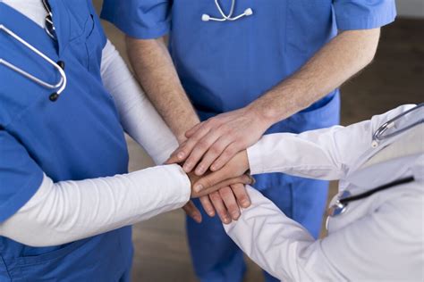 Foto di equipe medica e infermieristica che supporta un paziente oncologico con sorrisi e gesti di conforto