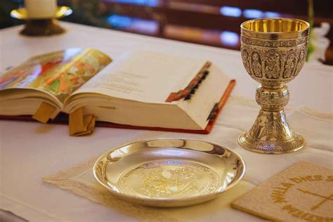 Sacerdote che bacia l'altare durante la Messa, con l'assemblea dei fedeli in sfondo.