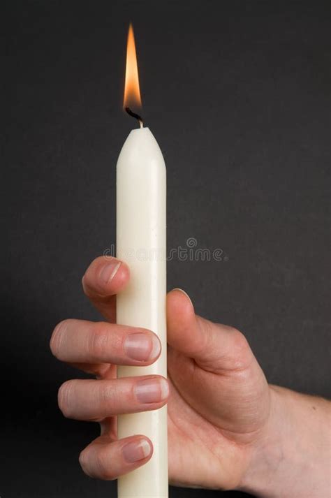 Mani che tengono una piccola candela accesa in un ambiente buio
