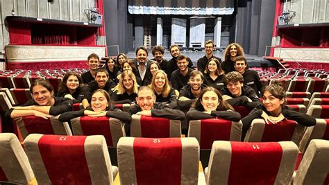 Giovani e adulti in un laboratorio teatrale, impegnati in esercizi di espressione corporea o vocale sul palco.