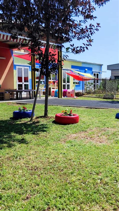 Veduta esterna di un asilo nido rinnovato con pareti di colore celeste e un giardino curato per bambini