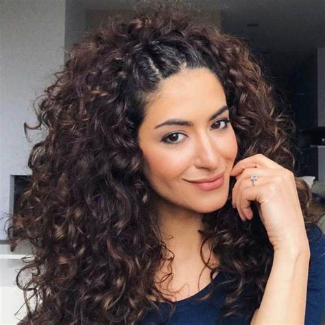 Ragazza con capelli ricci che indossa una mezzacoda con trecce morbide e fiori.