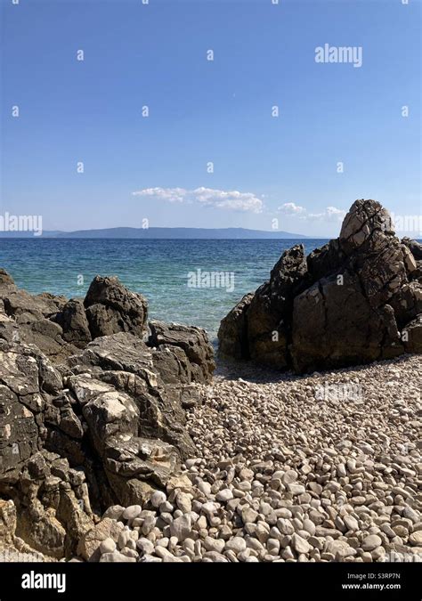 Foto della spiaggia di ciottoli di Santa Croce Mare con vista sui castelli di Miramare e Duino
